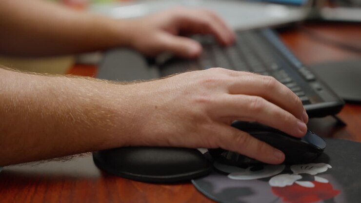 Hands using a keyboard and mouse at computer desk working in office