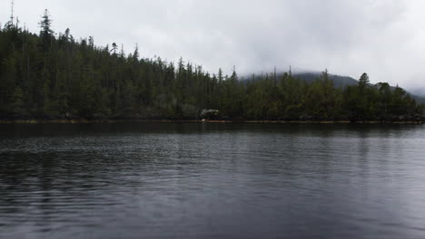 Antena-Baja-Sobre-La-Superficie-Del-Agua-De-Clayoquot-Sound-Hacia-La-Sauna-Flotante-De-La-Costa-Oeste