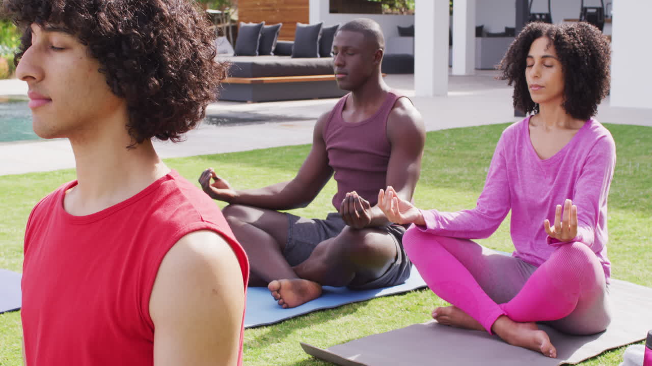 un grupo feliz de amigos diversos haciendo yoga en el jardín, meditando