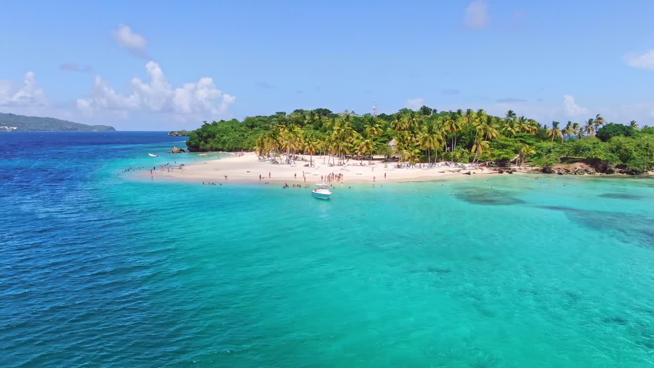 Ripresa aerea orbitante di molti turisti su un'isola di lusso con palme tropicali e acqua turchese - Cayo Levantado, Repubblica Dominicana