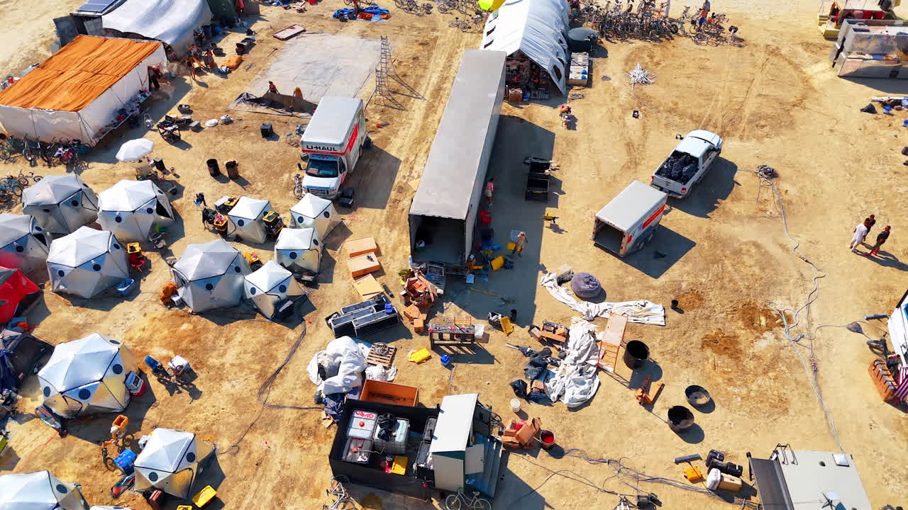 Rising over the camp with tents, vans and people doing their business. Aerial perspective on the campsite of Burning Man festival in the Black Rock Desert