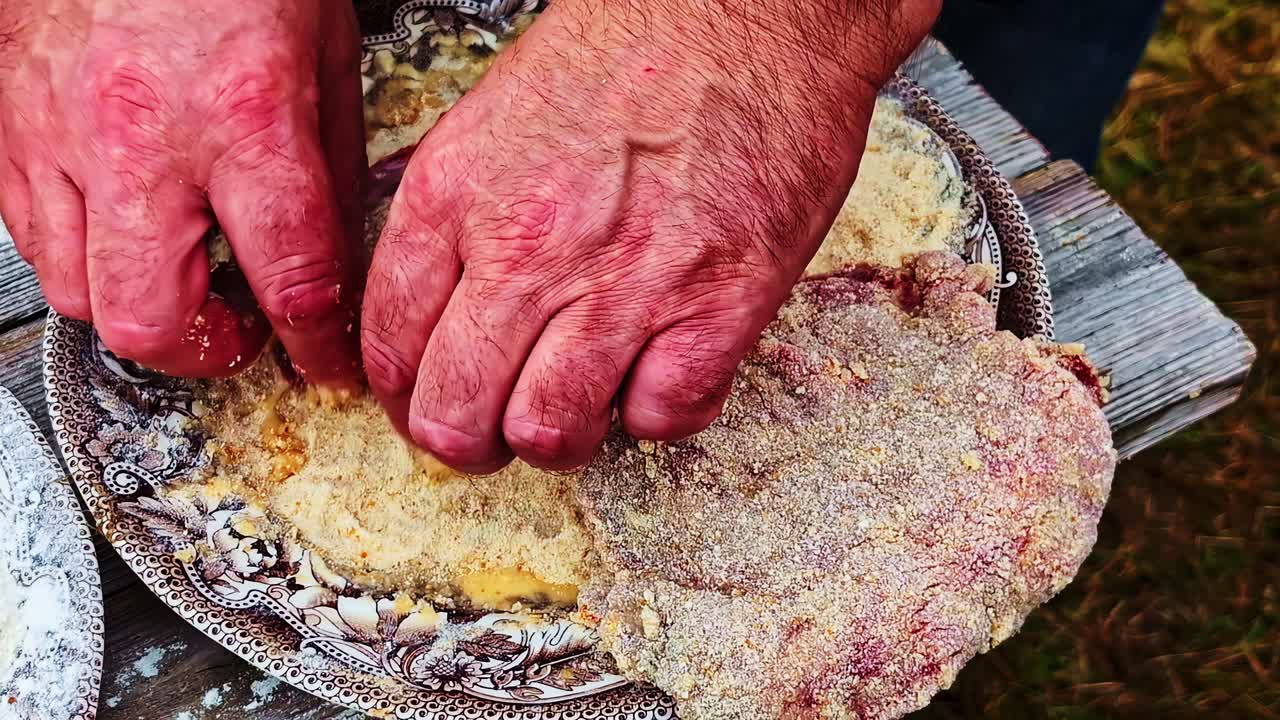 Hands dip meat into egg wash and coat it with bread crumbs for deep frying process