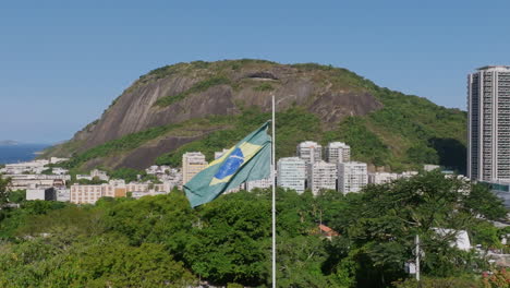 Imágenes-Aéreas-En-Cámara-Lenta-Girando-Alrededor-De-La-Bandera-De-Brasil-Moviéndose-En-El-Viento-En-El-Parque-Yitzhak-Rabin-En-Río-De-Janeiro