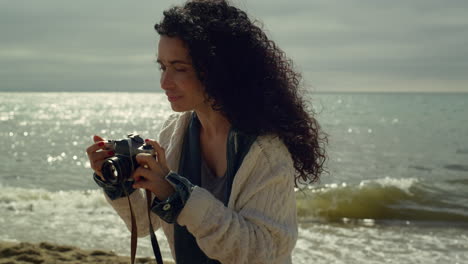 hispanic woman taking picture at seashore. pretty lady photographing nature.