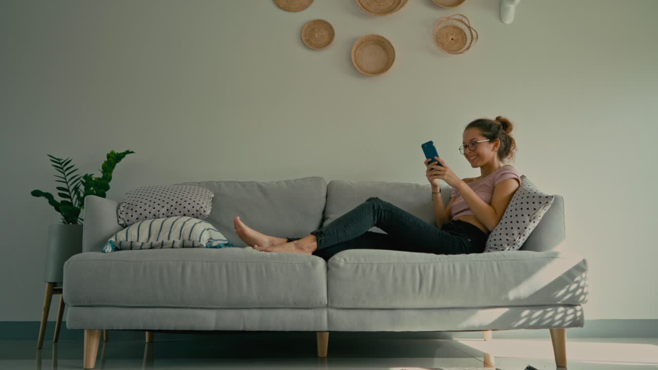 mujer relajándose en el sofá y usando el teléfono