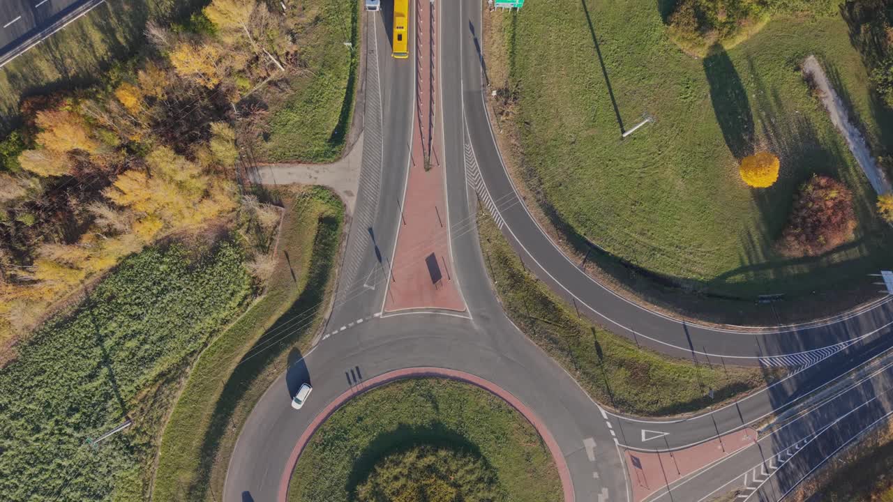 A top-down aerial view of a highway overpass showing cars and trucks traveling in both directions. Drone fly over the roundabout and highway while cars and trucks are moving through
