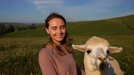 woman and alpaca in a sunny green field