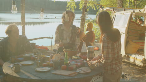 female friends preparing meal at lakeshore campsite