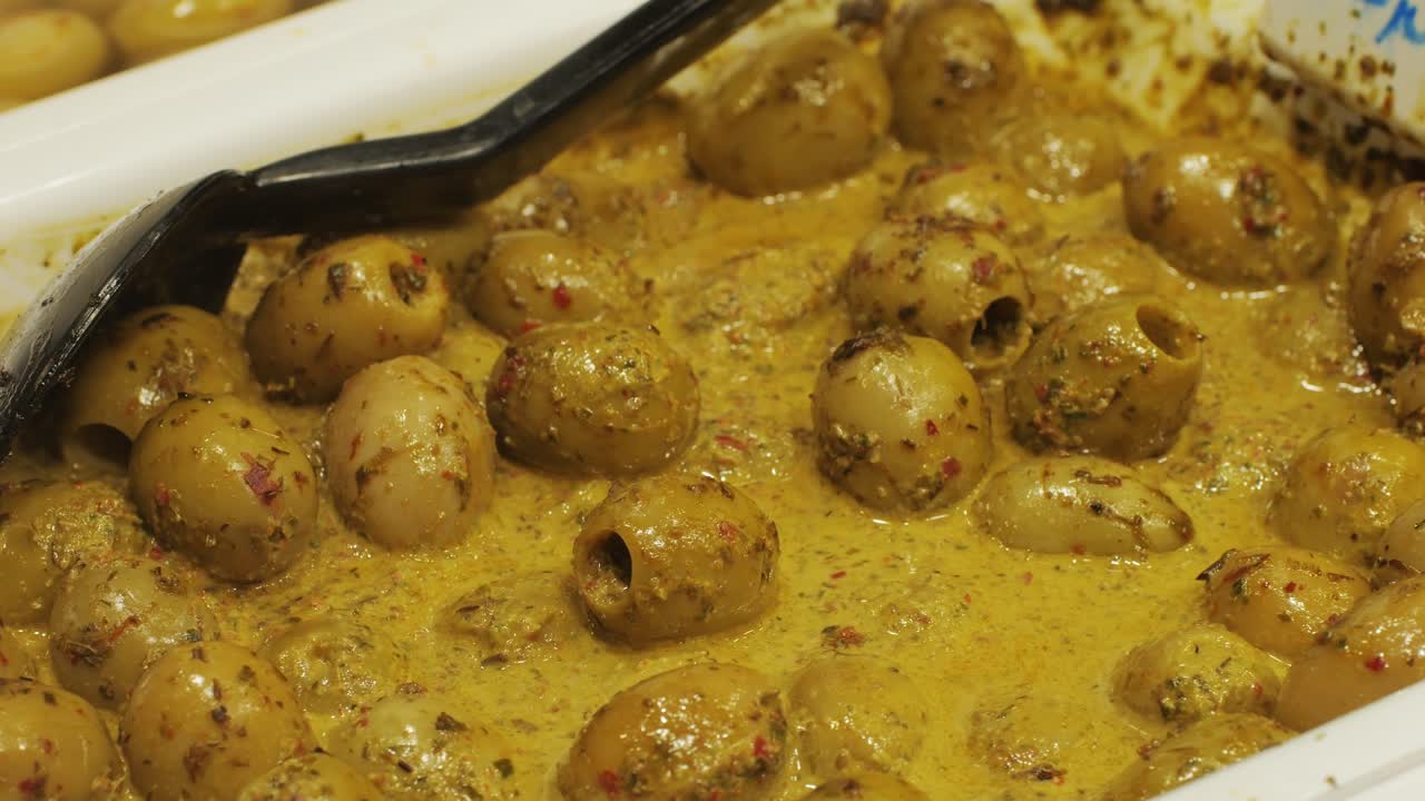 Marinated green olives in spicy sauce, spanish traditional food, ideal for Mediterranean dish or snack, market in barcelona.