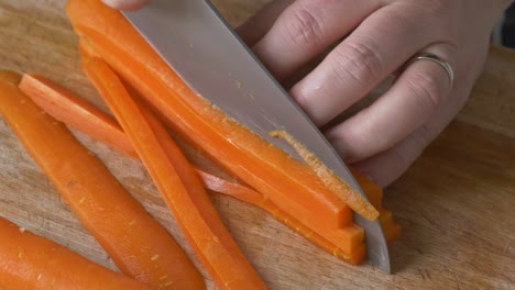 slicing stack of carrots on a wooden cutting board in a close up shot