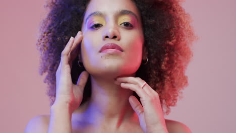 mujer biracial con cabello rizado oscuro en luz azul y rosa, cámara lenta
