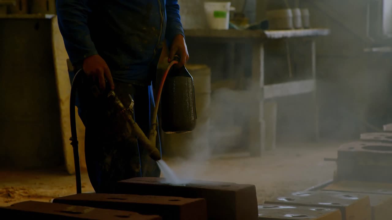 hombre rociando agua en moldes calentados en el taller 4k