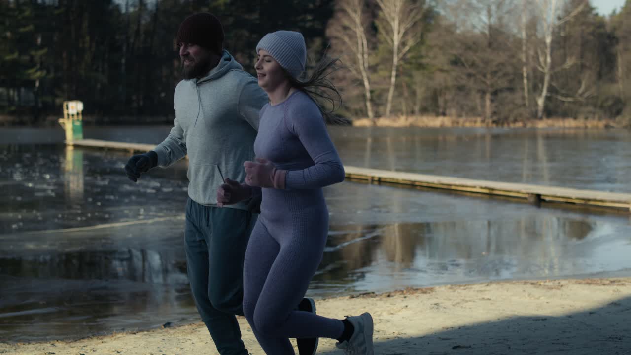 Adult caucasian couple jogging to warm up before winter swimming.