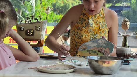 mother and daughter painting pottery