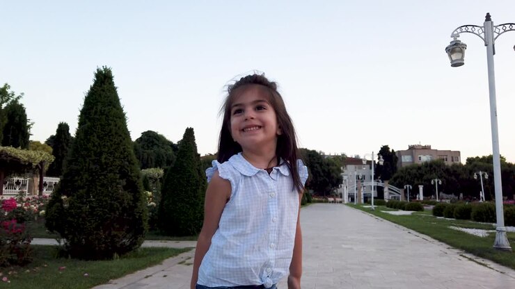 Cámara lenta: Niña pequeña y divertida actuando frente a la cámara en el parque