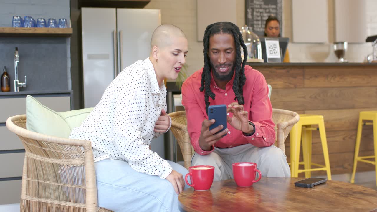Triggered by swiping smartphone, diverse friends leaning at cafe table sharing content and laughing