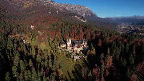 Castillo-De-Peles-Con-Bosque-Otoñal-Como-Telón-De-Fondo,-Bajo-La-Cálida-Luz-Del-Sol,-Vista-Aérea