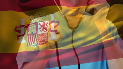 composición digital de la bandera de españa ondeando contra una trabajadora de la salud caucásica que sostiene un estetoscopio