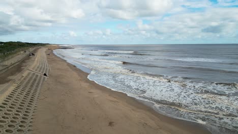 Balneario-Inglés,-Filmado-Con-Un-Dron,-Que-Ofrece-Un-Punto-De-Vista-Aéreo-Alto-Que-Muestra-Una-Amplia-Extensión-De-Playa-De-Arena-Con-Un-Muelle-Y-Olas-Rompientes