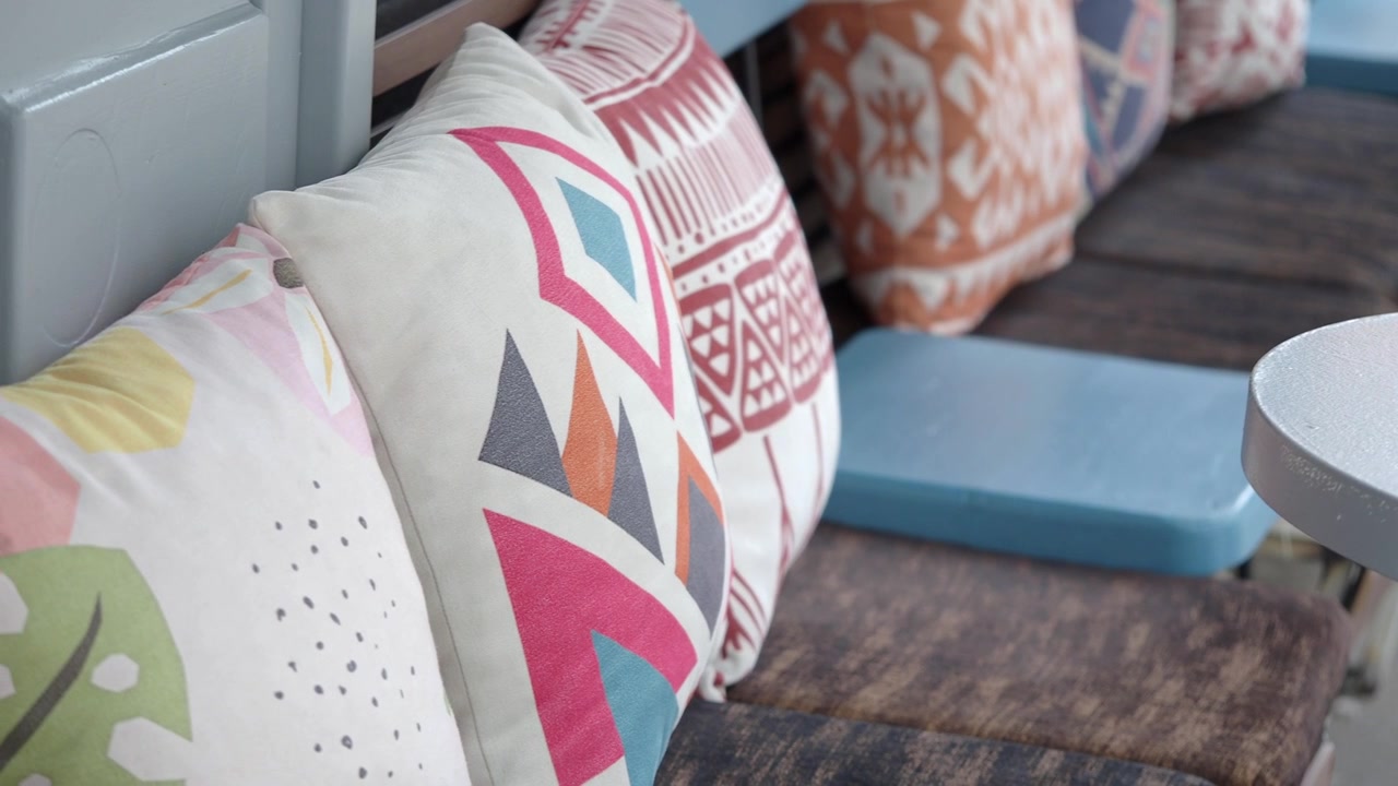 Decorative Patterned Pillows on a Bench in a Cafe