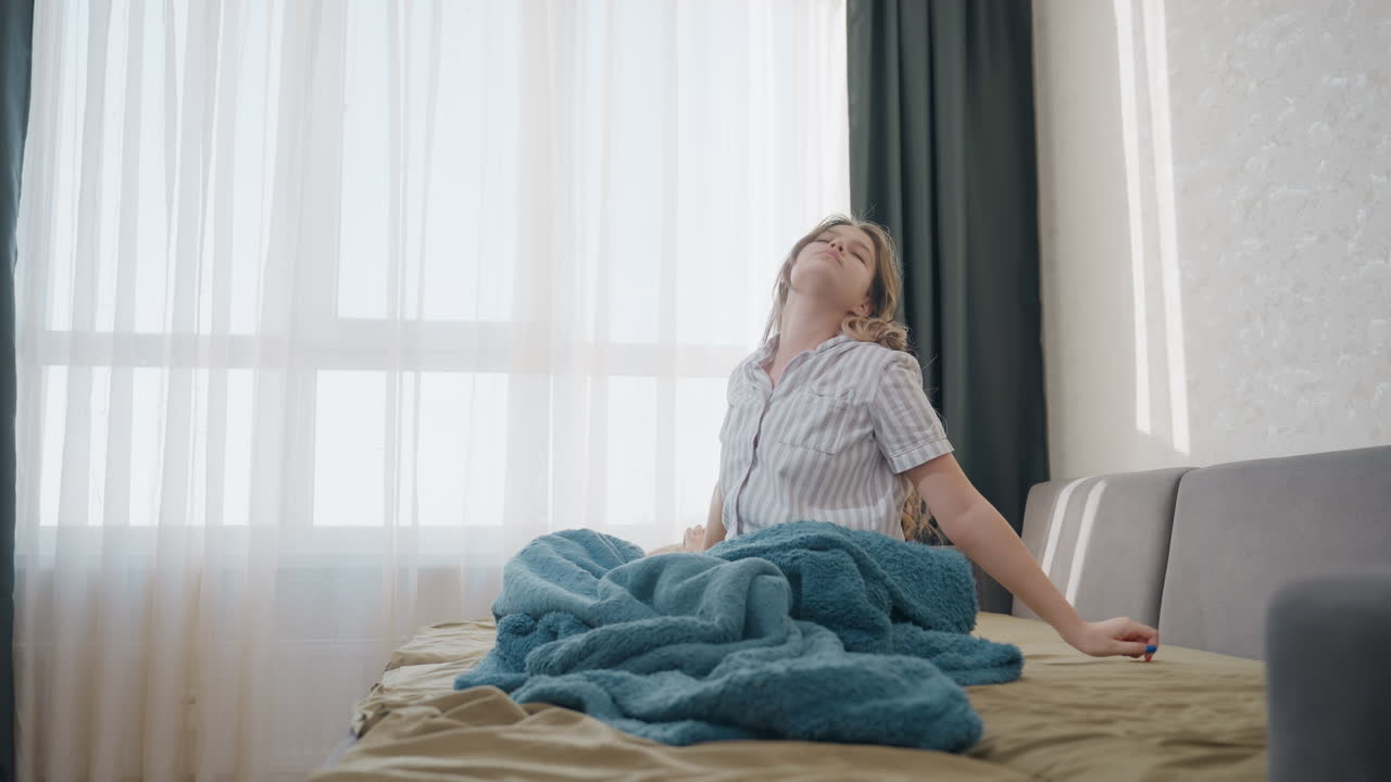 White Teenage Girl On Bed Crying, Covering Face And Rubbing Eyes, Soft Sunlight Through Curtains, Blue Blanket Draped Over Knees, Quiet Bedroom Mood, Slow Breathing And Inward Reflection