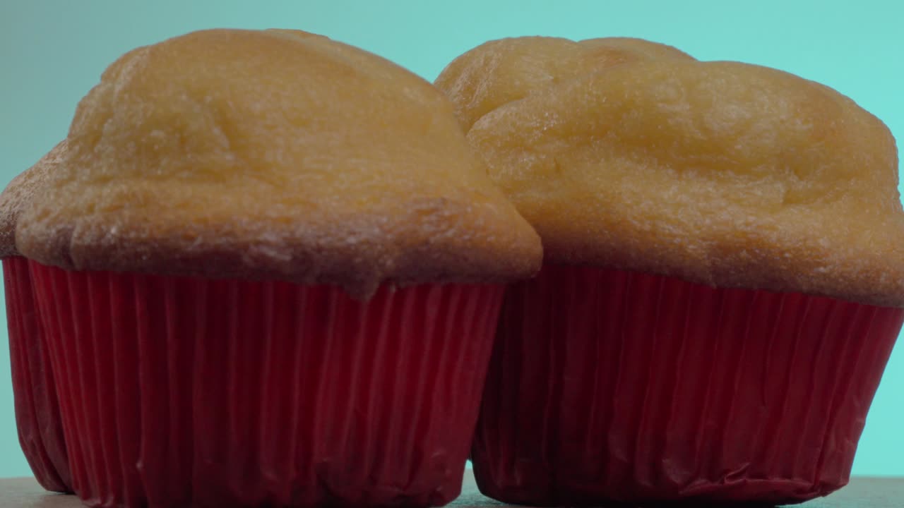 Cupcake morbidi e soffici sono esposti su una superficie di legno. I pirottini rosso vivo contrastano splendidamente con le cime dorate, invitando a uno sguardo più attento mentre si raffreddano