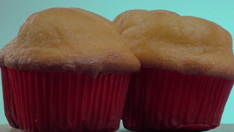 los pasteles suaves y esponjosos se exhiben en una superficie de madera. los revestimientos rojos brillantes contrastan hermosamente con las tapas doradas, invitando a una mirada más cercana a medida que se enfrían.