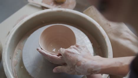 female potter makes a pot on the pottery wheel.