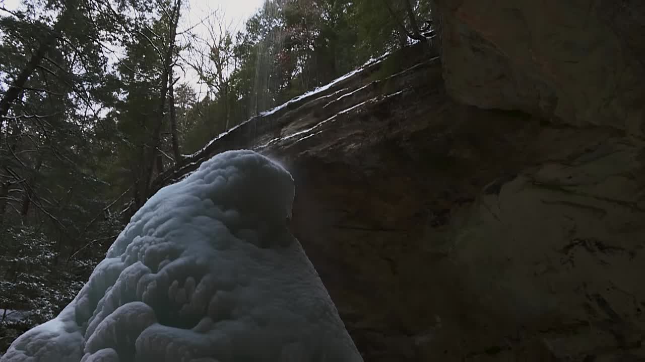agua que fluye hacia abajo en el cono de hielo formado bajo la cascada durante el invierno en la cueva de cenizas en el clip de la cueva de cenizas 18