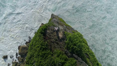 aerial top view of man while he is sitting on the edge of a cliff