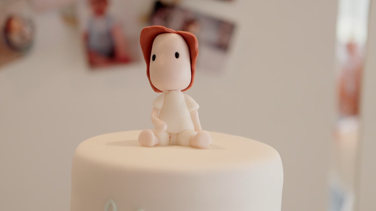 minimal fondant baby figurine with red hair sitting on top of simple white cake