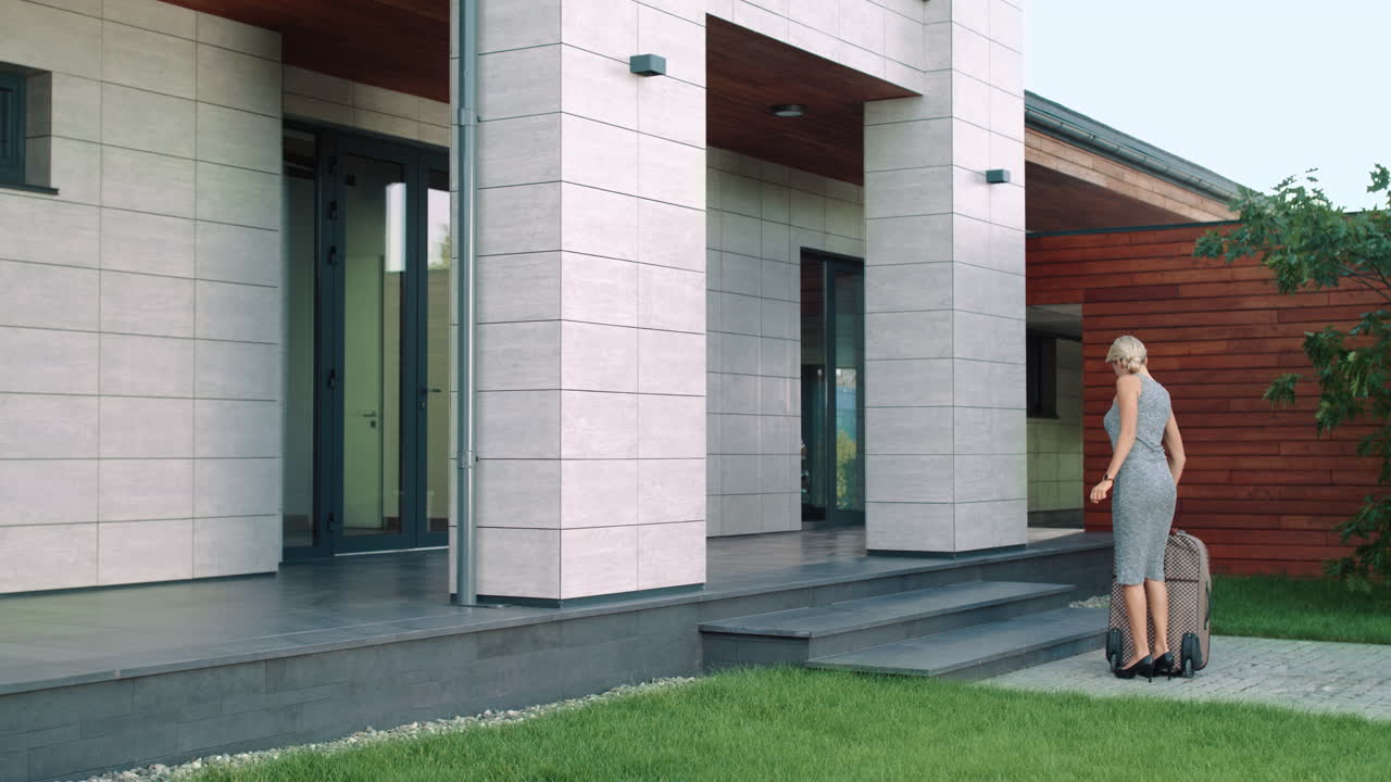 деловая женщина входит в богатый дом с чемоданом. женщина-путешественник входит в отель