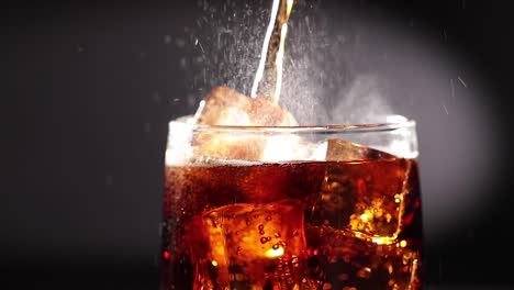 cola con hielo y burbujas en cámara lenta de vidrio.