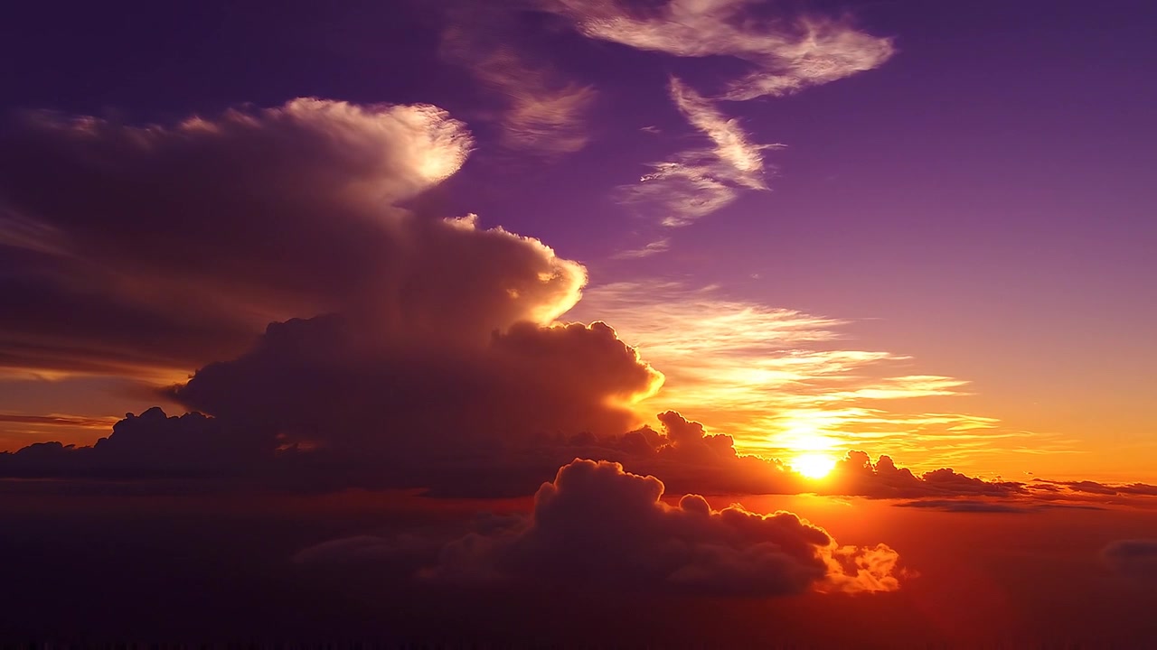 Dramatischer Sonnenuntergang über dichten Wolken mit lila und orangefarbenem Himmel