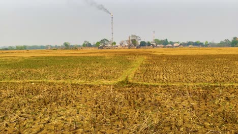 Pan-down-from-flaring-gasplant-reveals-dry,-cracked-soil-and-dead-crops