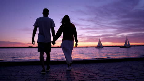 couple walking hand in hand at sunset on the beach