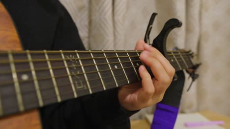 close-up of caucasian person playing chords on acoustic guitar