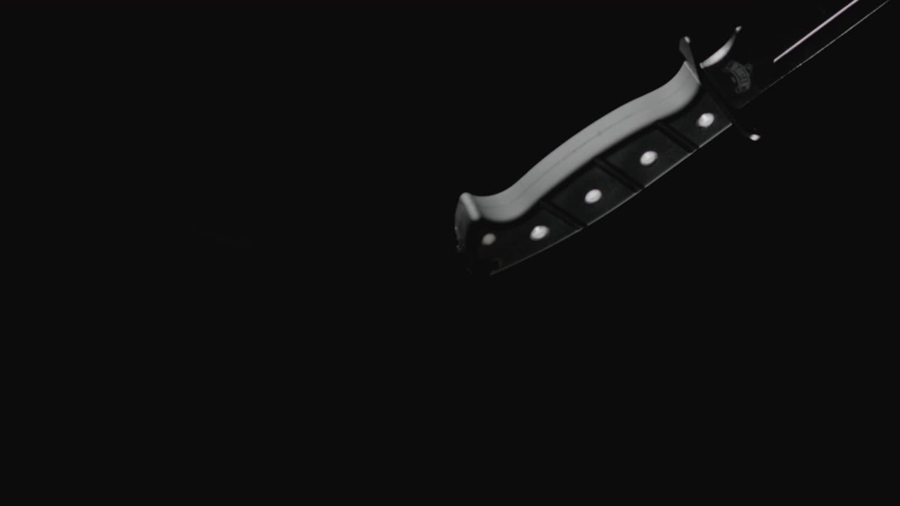 Knives on the dark background are falling in slowmotion