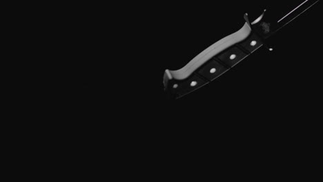knives on the dark background are falling in slowmotion