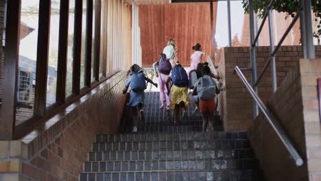 Verschiedene-Schulmädchen-Mit-Schultaschen-Laufen-In-Zeitlupe-Auf-Treppen-In-Der-Grundschule