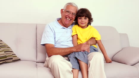 un anciano sentado en el sofá con su nieto jugando al ajedrez.
