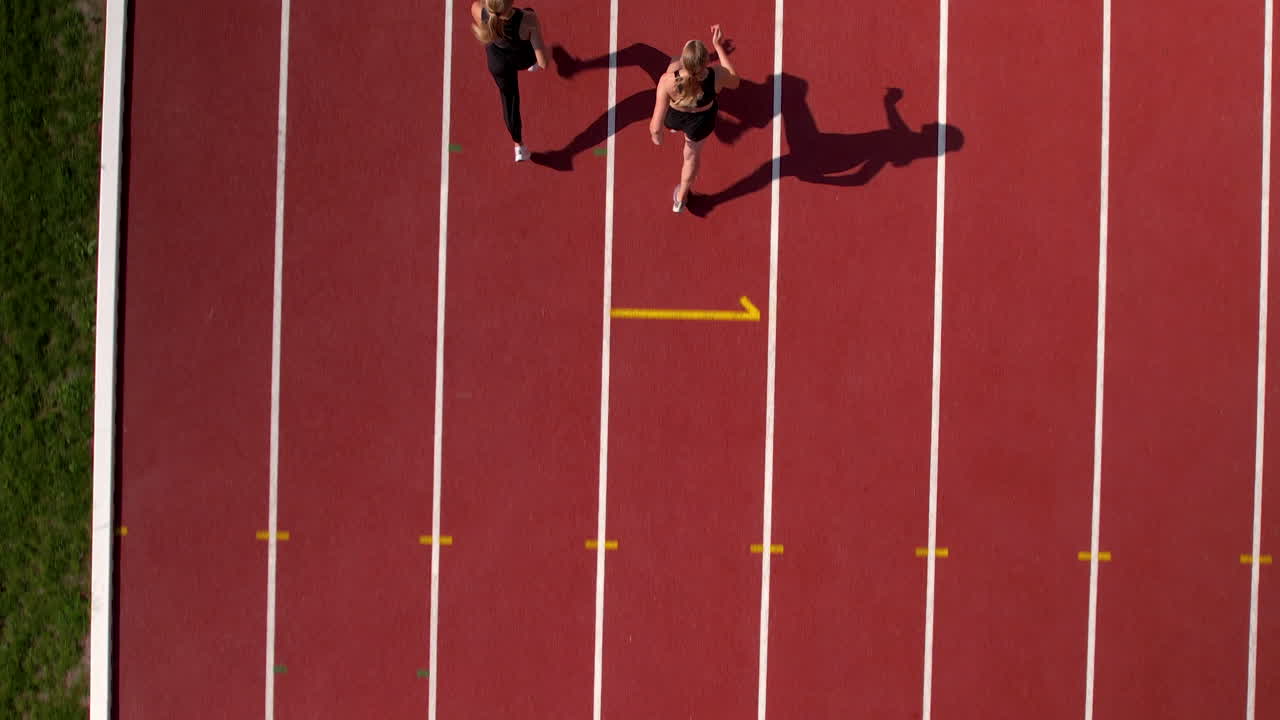 Two Female Athletes Running on a Track