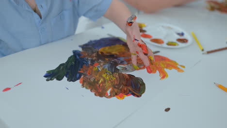 close-up children draw their fingers on paper using paints