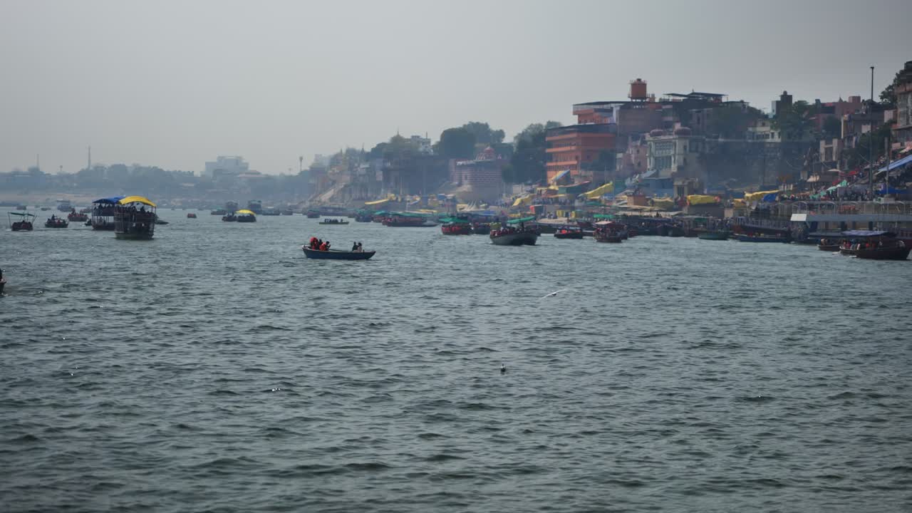 Boats moving in ganga river with surround haze and flying birds at kashi, varanasi, uttar pradesh, india. day time, stable shot, 4k.