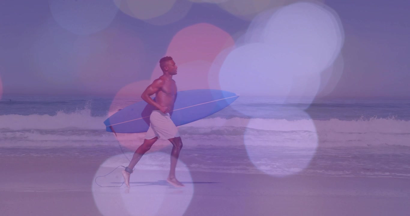 Video verticale: surfista uomo sportivo che si prepara con la tavola blu sulla sabbia, con una sovrapposizione di effetto bokeh viola, per fare surf.
