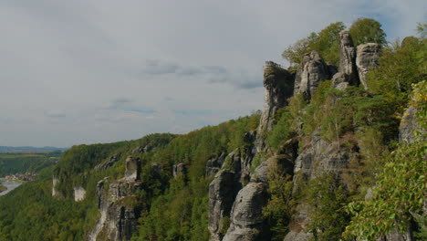 observation platform elbsandsteingebirge sachsen elbe sandstone formations rising above dense green forests mountains, under a blue sky with scattered clouds natural beauty and rugged terrain
