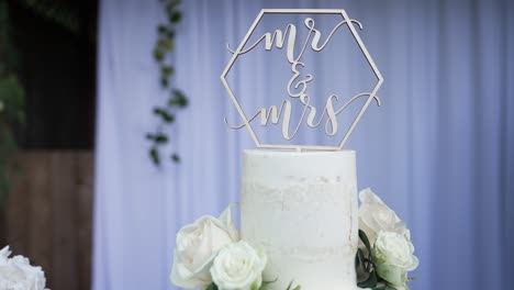 beautiful wedding cake decorated with natural flowers and a cake topper on the tip