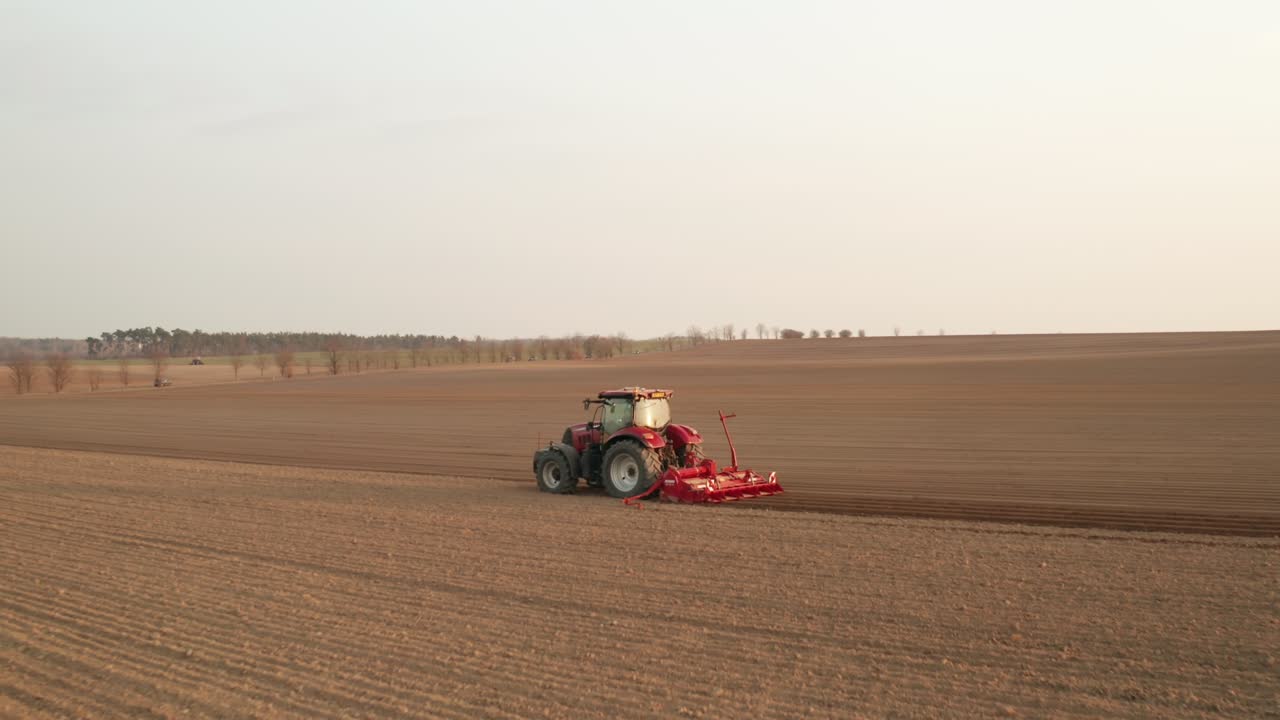 vista aérea de un tractor agrícola rojo sembrando trigo en el campo. comienzo de la temporada de siembra