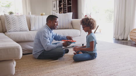 Pre-teen-girl-and-grandad-sitting-on-floor-in-living-room-high-five-after-building-a-toy,-side-view