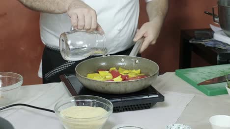 a chef preparing veg ball stock by sauteing red and yellow capsicum on induction